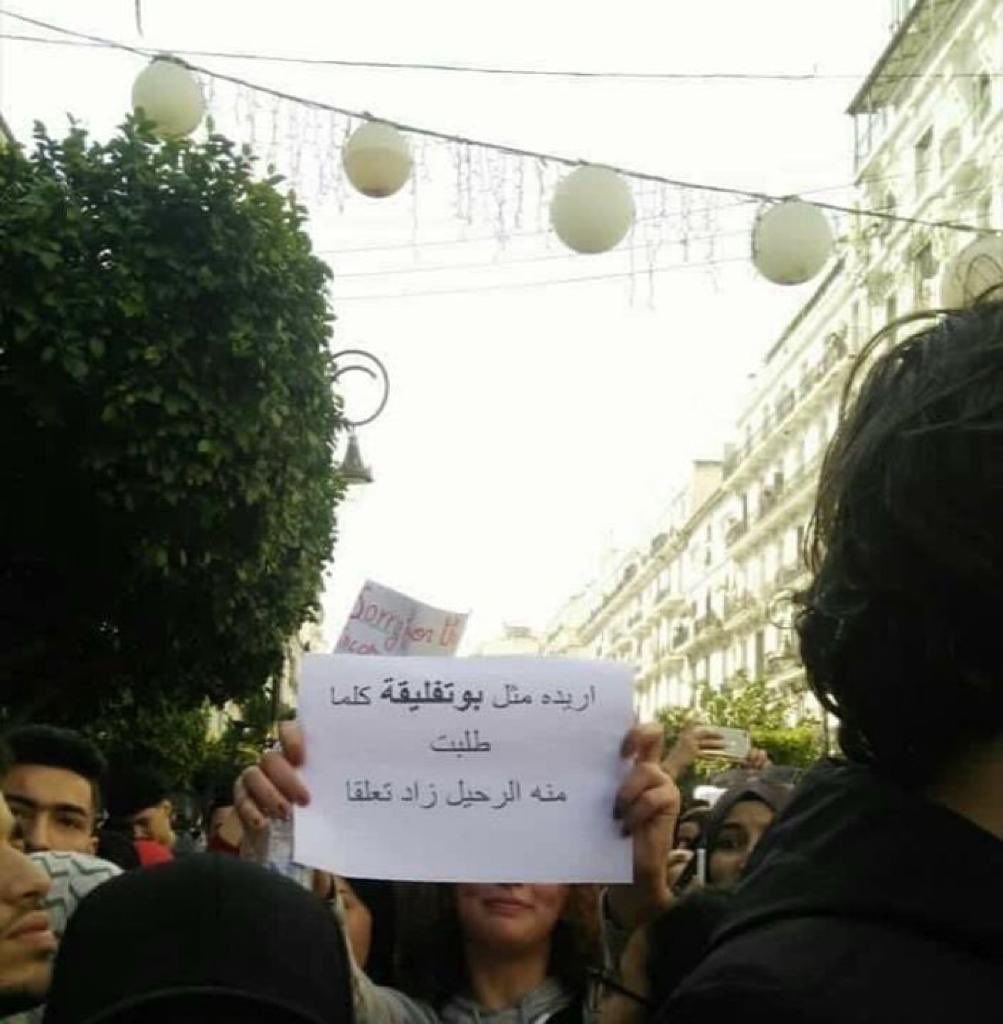 Algerian woman held a sign in Algeria protest that read I want him just like Bouteflika, the more I ask him to leave, the more he gets attached 